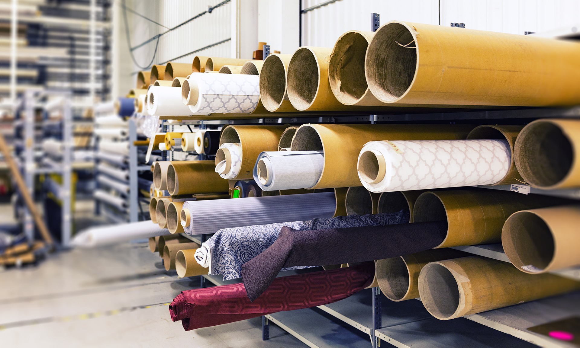 Rolls of fabric on a storage cart in a factory.