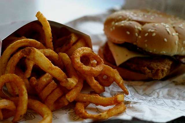 Close up image of curly fries and a fast-food chicken sandwich.
