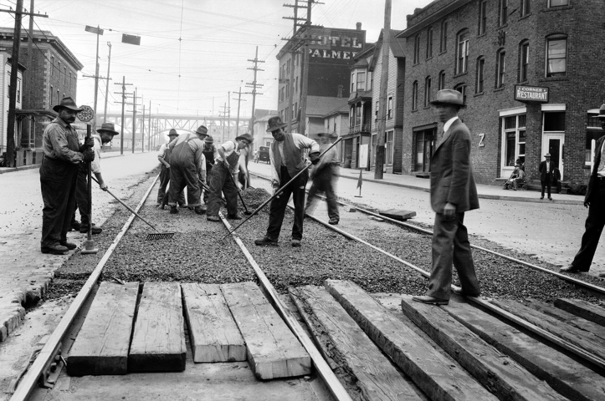 Image of a group of men in the early 1900's working on paving a city road.