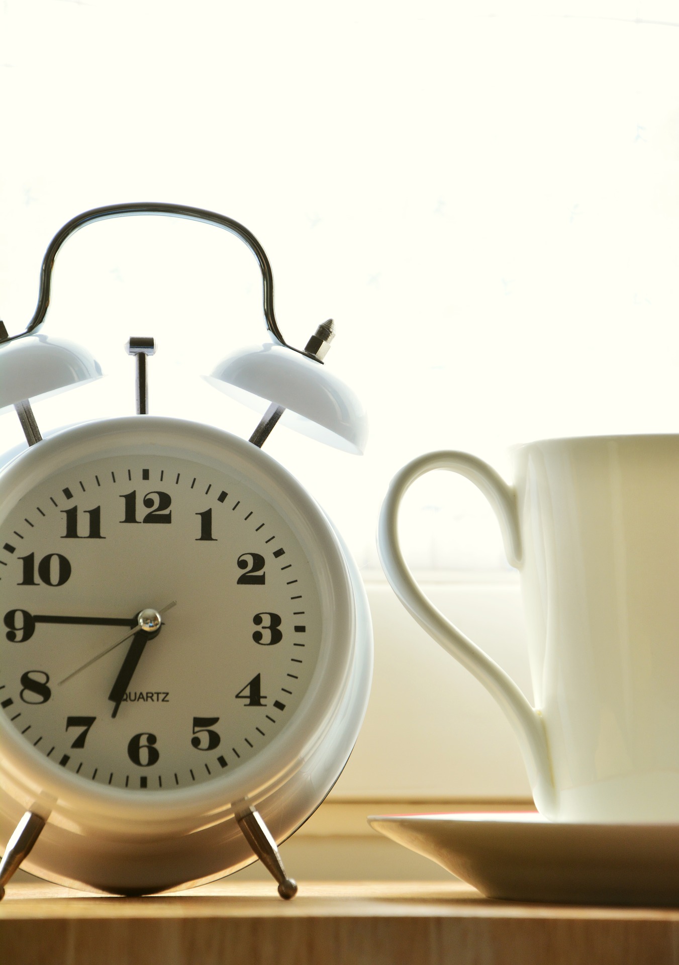 an alarm clock next to a mug.