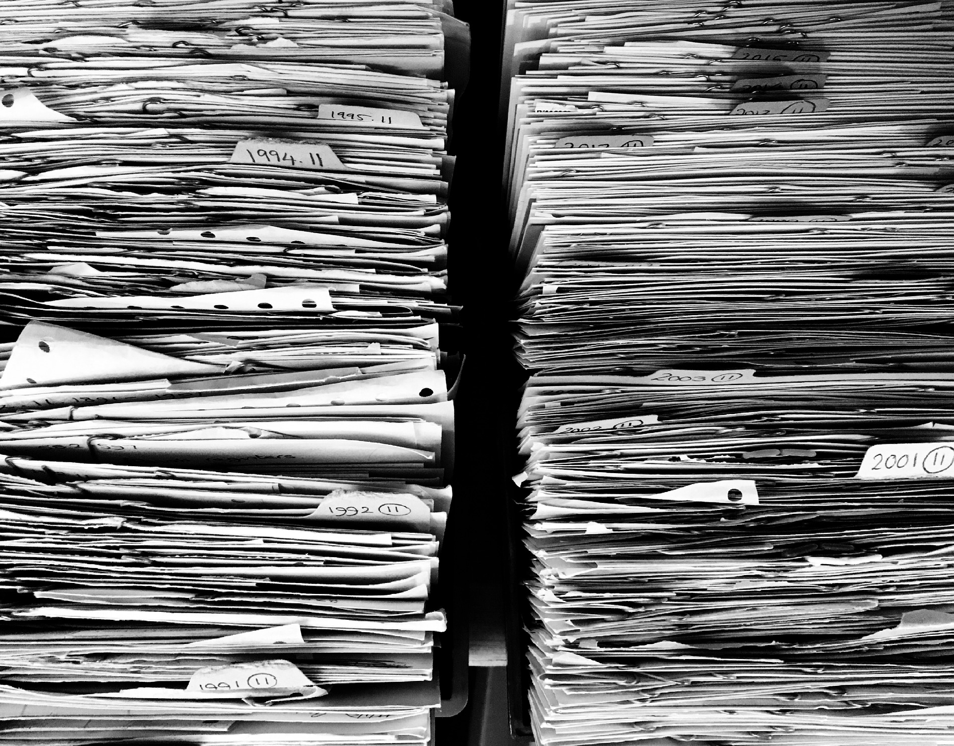 Stacks of papers with makers separating annual segments from the year 1991 to 2012.