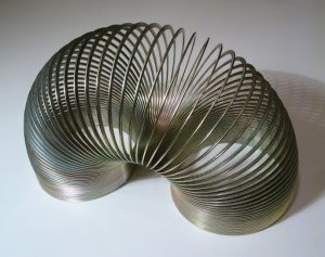 Metal slinky with both ends resting on a table.
