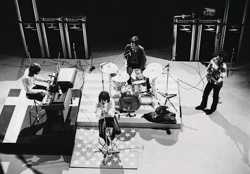 Black and white ariel view of Jim Morrison and 3 other band members on stage.