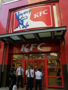 Three workers stand outside of a KFC in China.