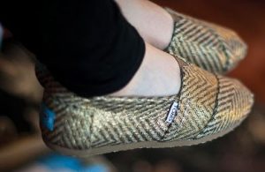 Close up picture of someone wearing a pair of metallic chevron alpergata TOMS.