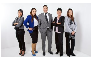 Four women and one man in business attire posing in front of a white background.