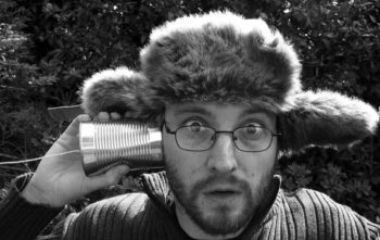 Humorous photo of a guy in a beaver hat holding a soup-can "telephone" to his ear.