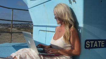 Photo of woman sitting on a boat working on her laptop.