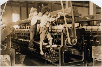 Black-and-white photo of two children standing and working on mill machinery