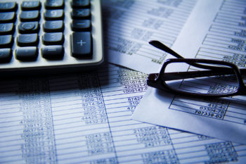 Photo of calculator, balance sheets, a pair of reading glasses 
