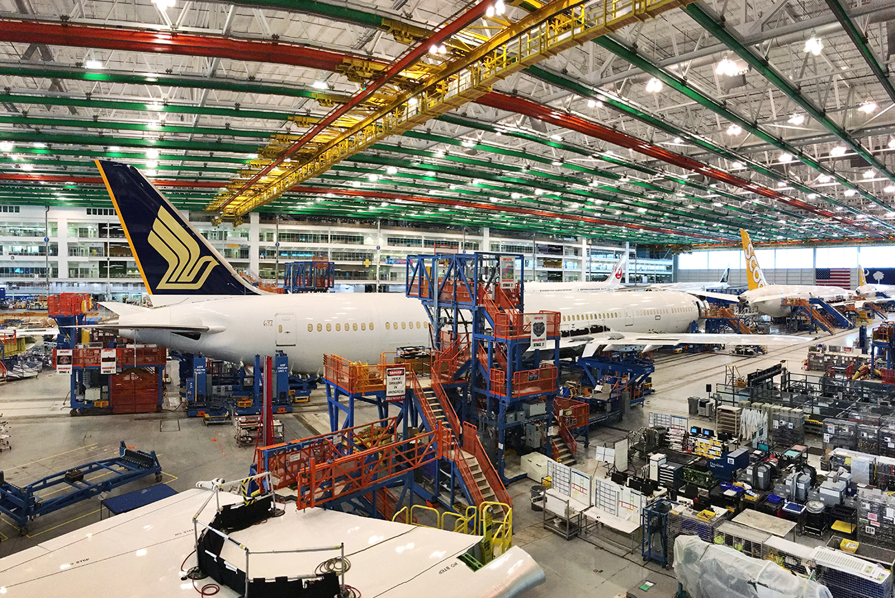 A photograph shows a large indoor area filled with airplanes, and machines and computers.