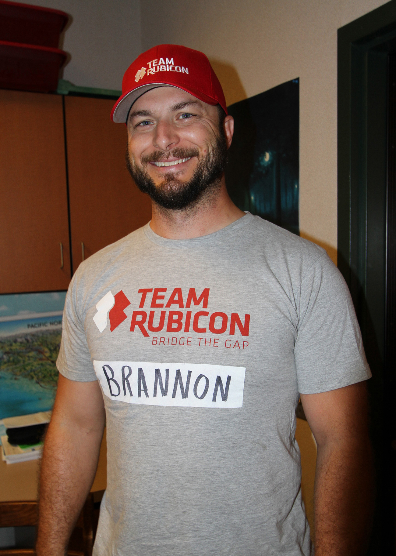 La photographie montre un homme portant une casquette Team Rubicon et une chemise Team Rubicon.