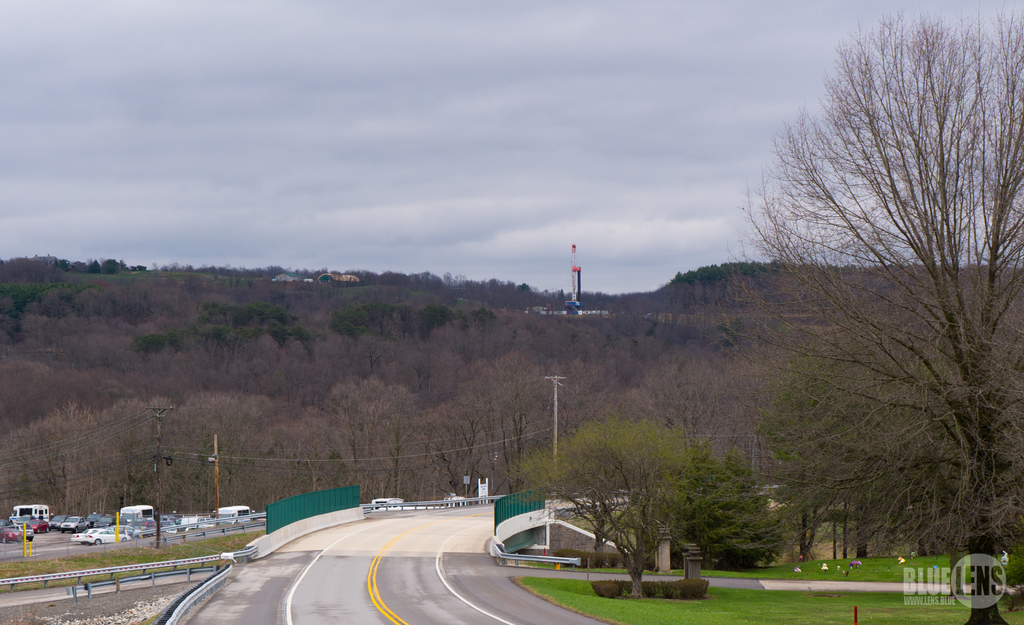 一张照片显示的是乡村景观，远处的山上有一个大型的高科技钻机。