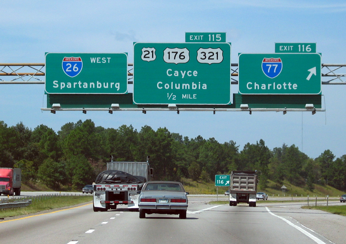 A photograph shows a highway with large signs that signal Spartanburg is on Interstate 26 west, and Charlotte in on Interstate 77.