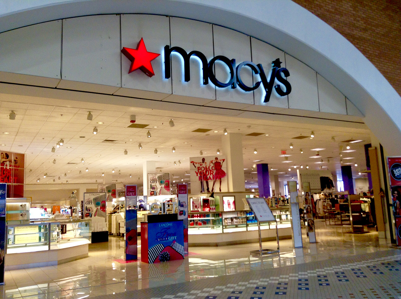 Photograph shows the brightly lit entrance to a Macy's department store.
