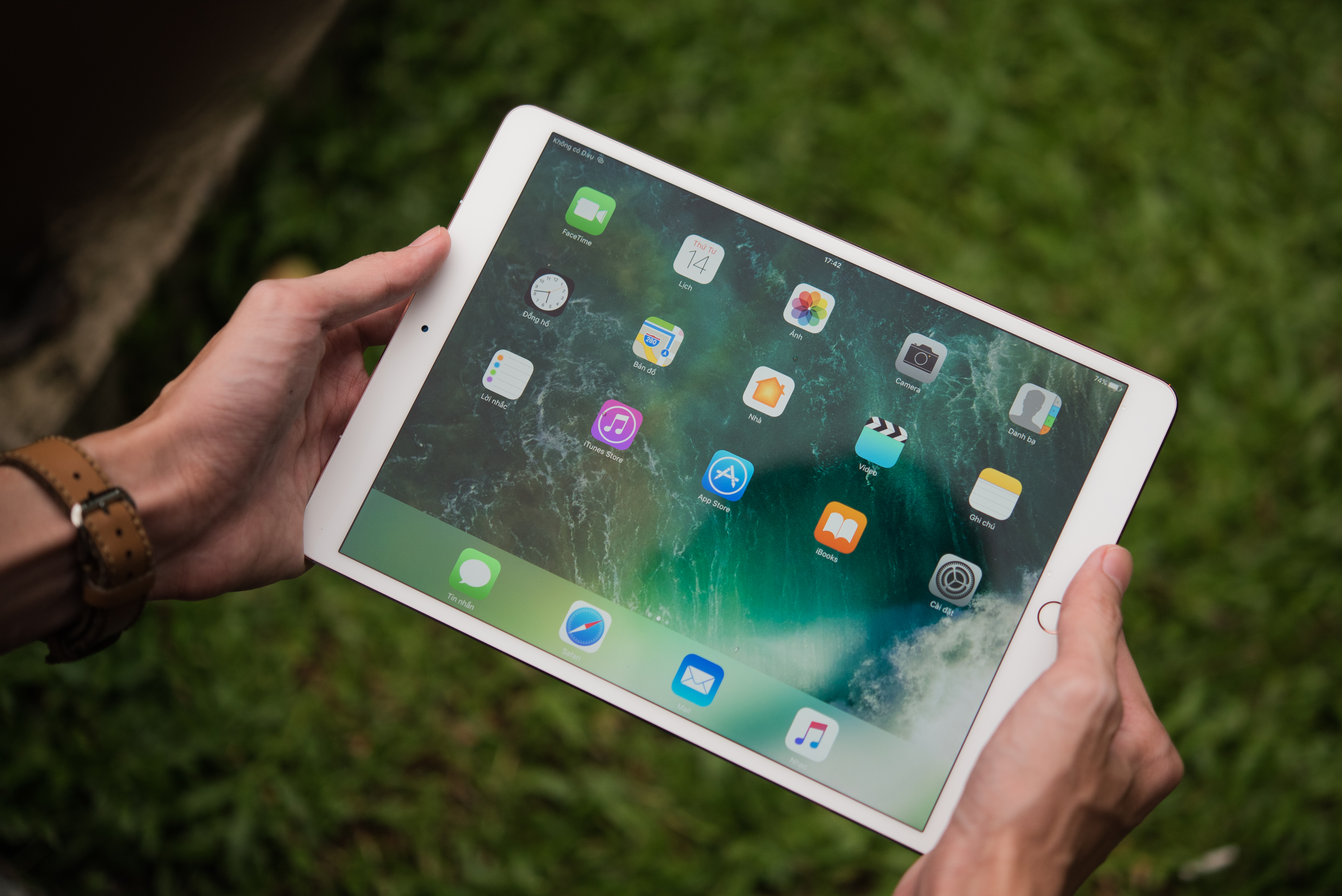 Uma fotografia mostra uma pessoa segurando um iPad pro. Existem widgets e aplicativos coloridos na tela.