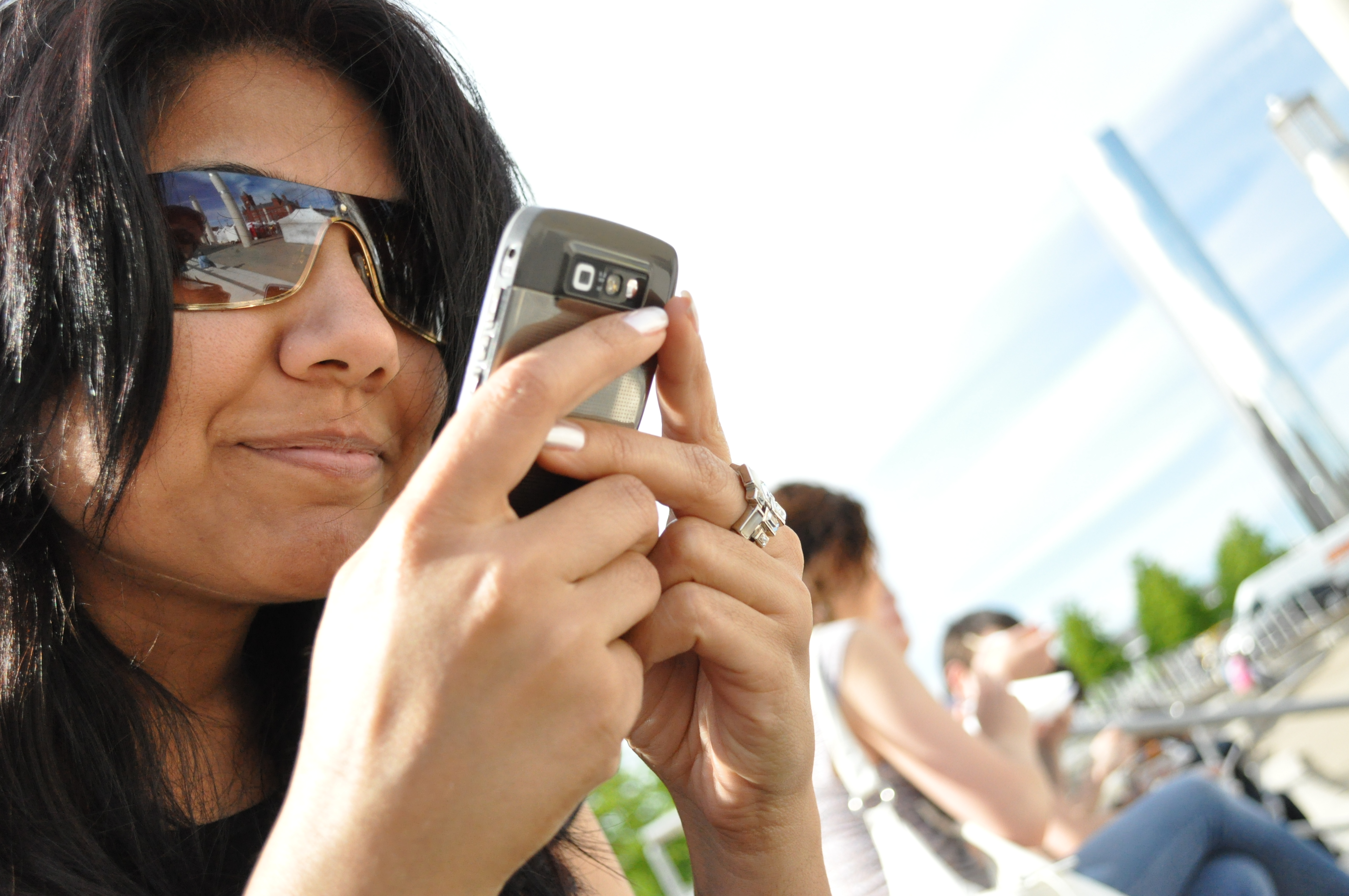 Une photo montre une femme tenant un téléphone près de son visage alors qu'elle envoie un texto à quelqu'un.