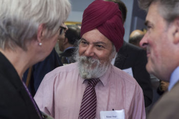 Photo of two men and one man in a business setting. One man wears a turban.