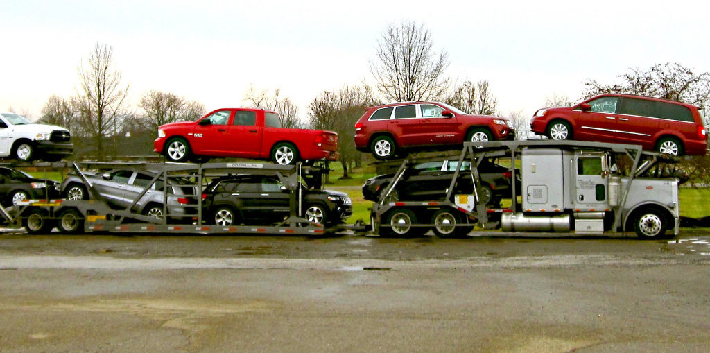 Large truck loaded with new cars.
