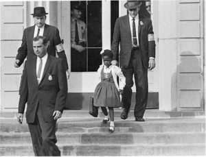 Photo of U.S. marshals with young Ruby Bridges on the steps of the William Frantz Elementary School. 
