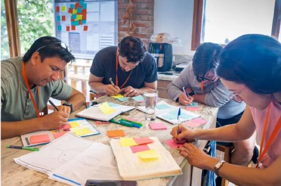 4 people at a table writing postit notes
