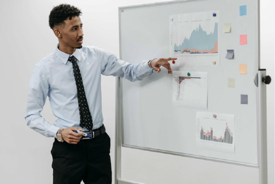 Man presenting using a whiteboard with graphs