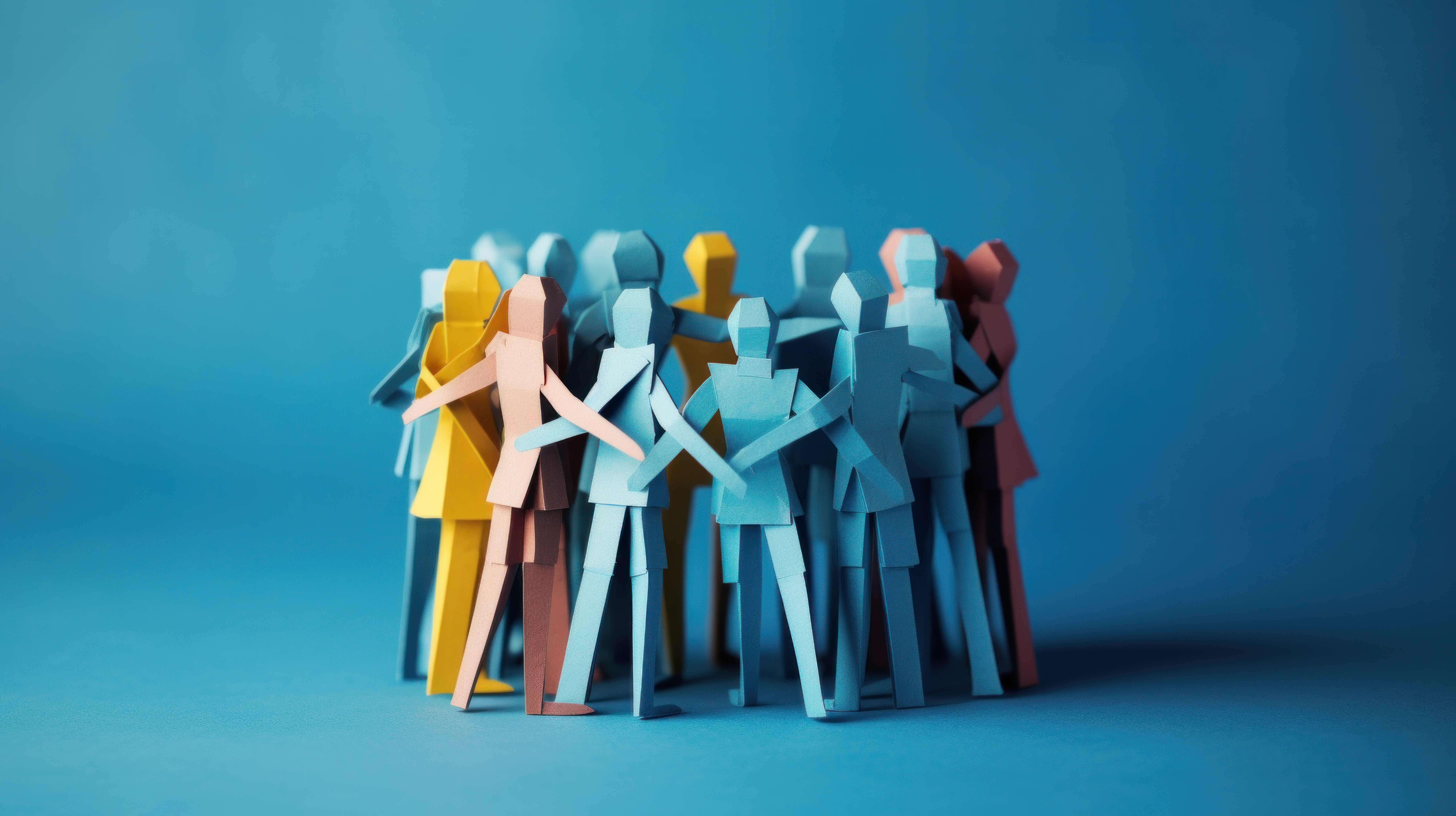 A group of colorful paper figures standing close together against a blue background, embodying unity and diversity.