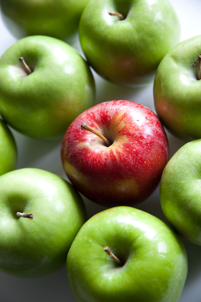 Foto de siete manzanas verdes alrededor de una manzana roja
