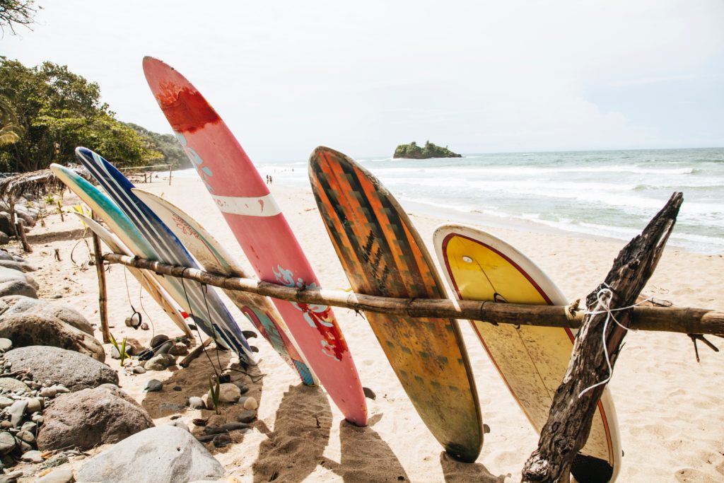 7 tablas de surf bien usadas se apoyan contra un estante en la playa.