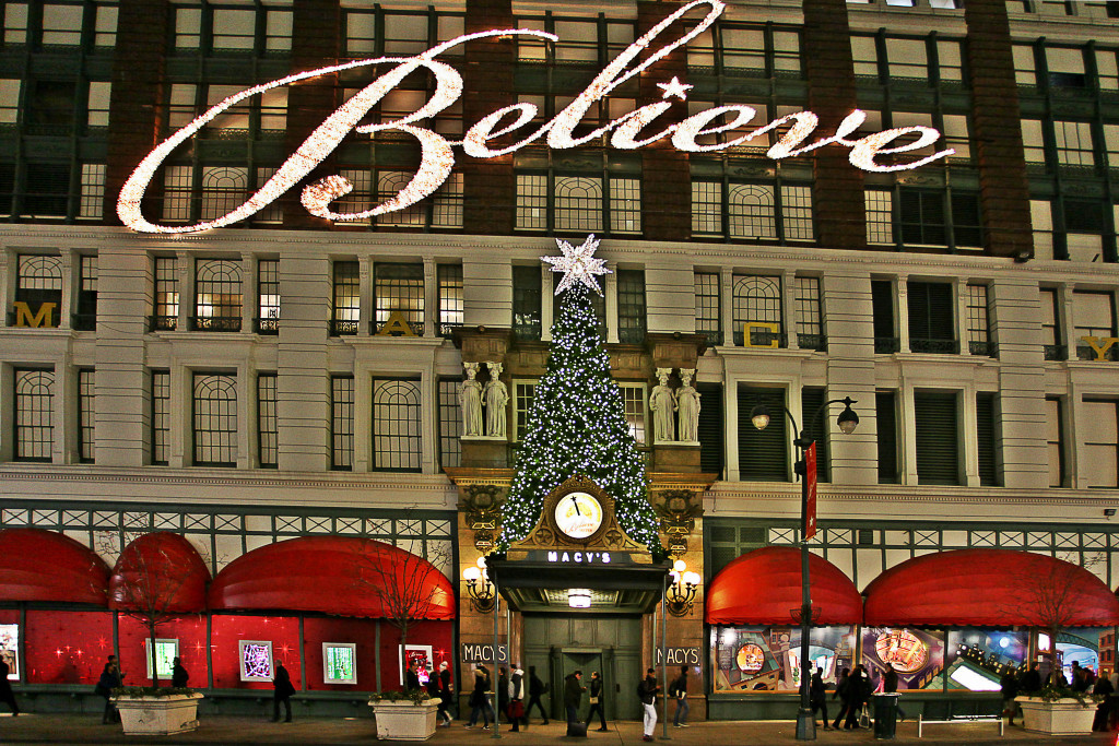Vista frontal de los grandes almacenes Macy's en la ciudad de Nueva York, decorada en Navidad con un gran letrero blanco iluminado que deletrea la palabra “Believe”.