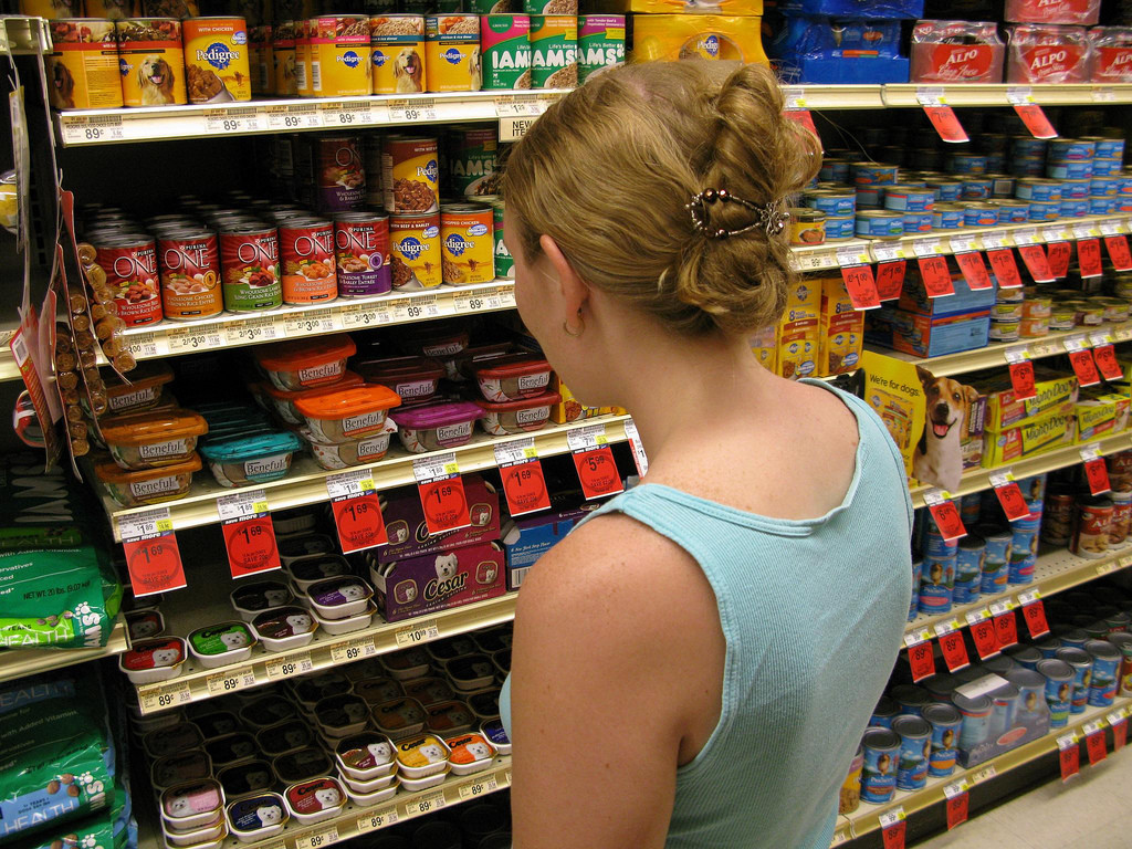 View of woman at grocery store looking at dog food selection.