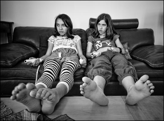 Two teenage girls on couch, Wii remotes in hand.
