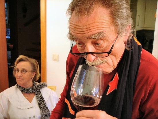 Picture of an elderly man sniffing a glass of red wine before tasting.