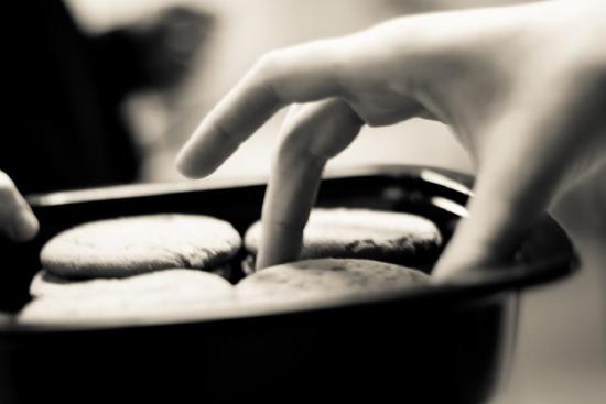 A hand plucking cookies out of a platter.