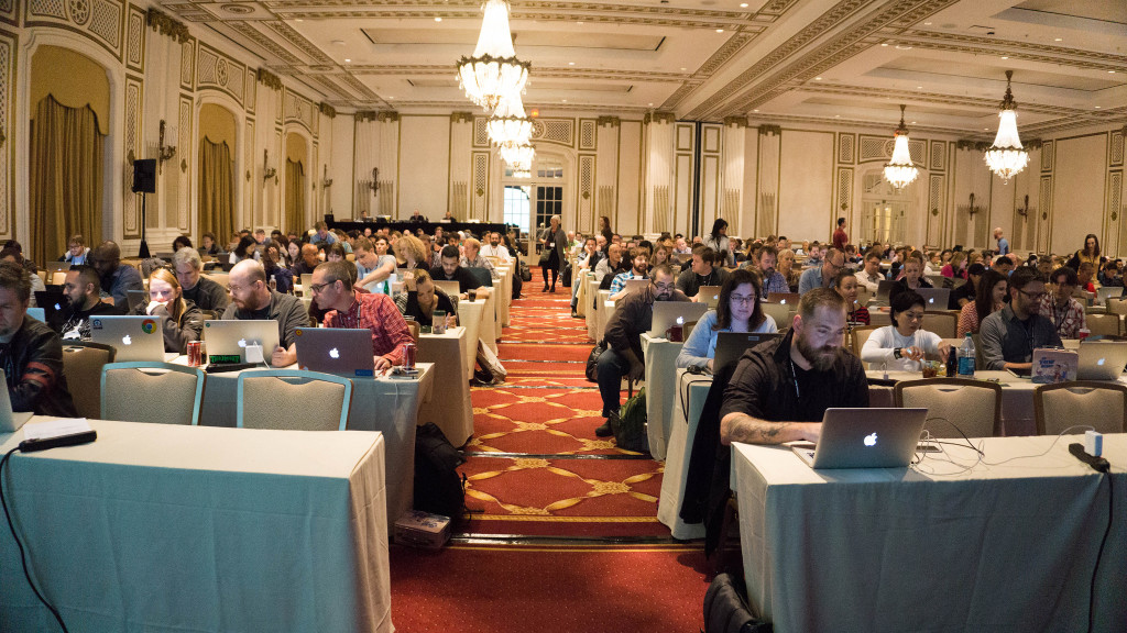 Una sala de conferencias llena de gente sentada con computadoras portátiles en las mesas.
