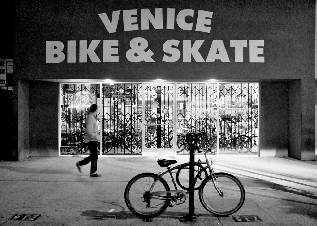 A man looks at the storefront for Venice Bike & Skate shop as he walks by.
