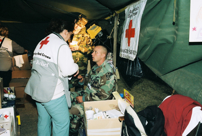 American Red Cross members interacts with seated soldier